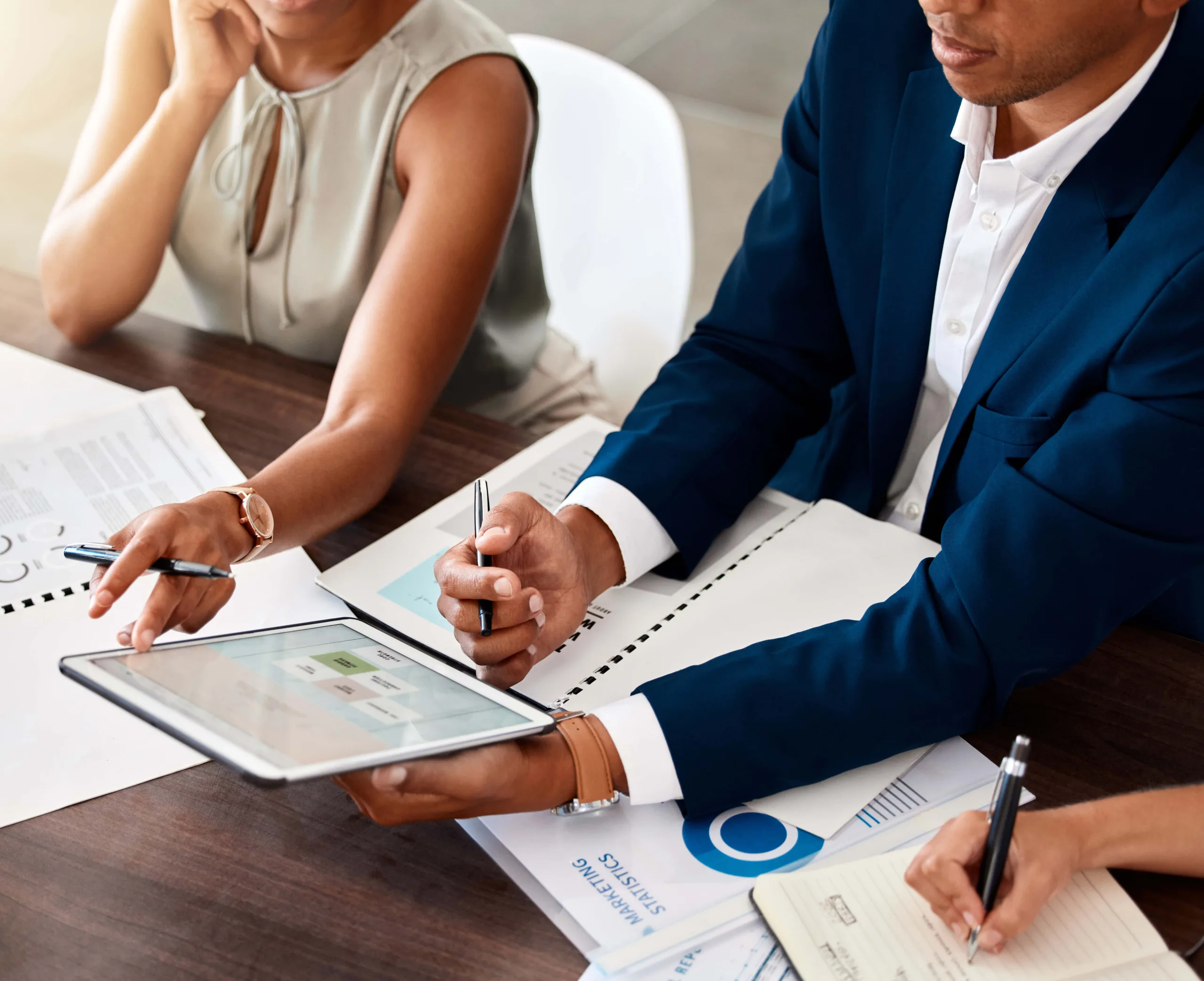 Business manager holding digital tablet presenting financial data to colleagues in a meeting