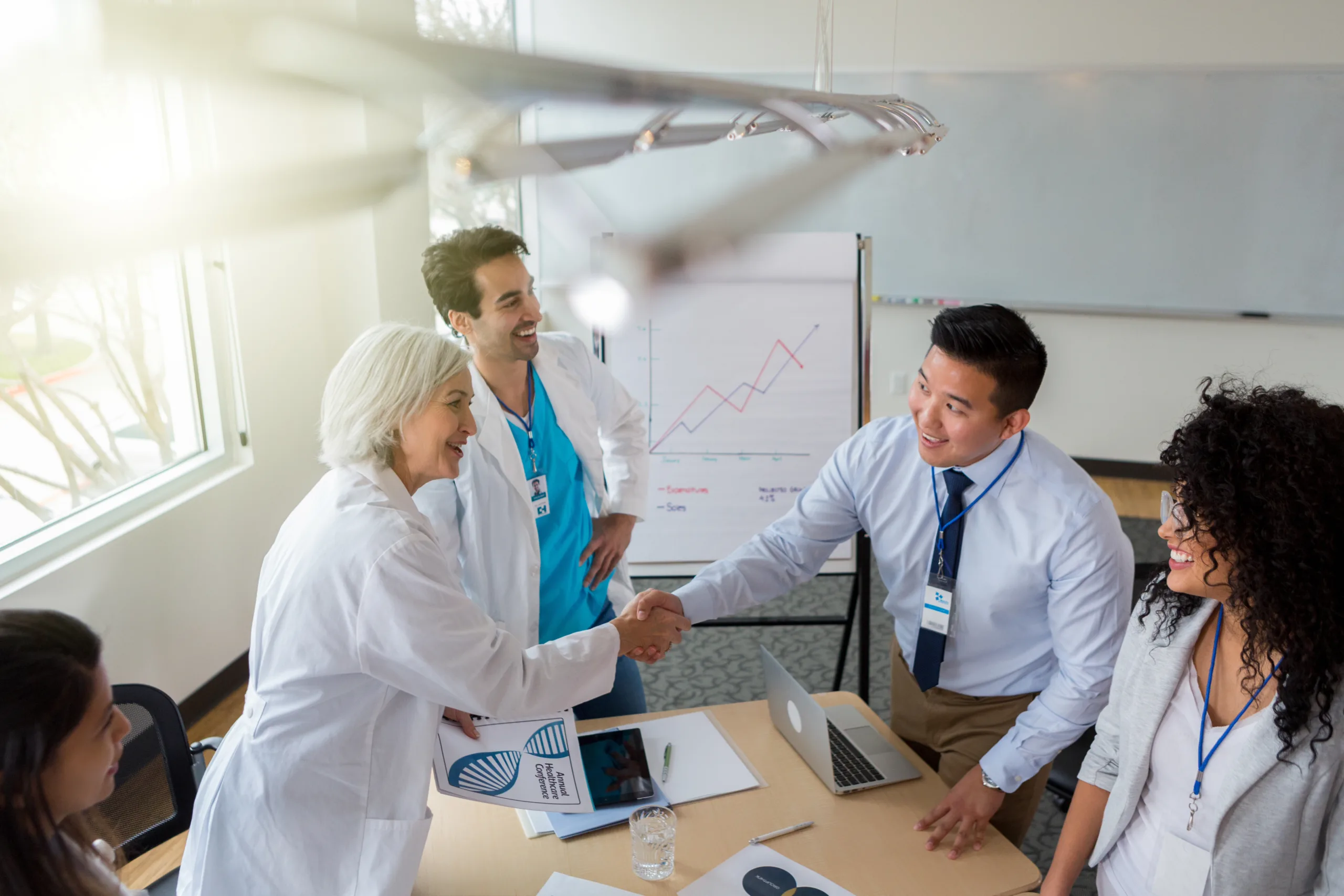 female doctor shakes hands with male hospital administrator before meeting