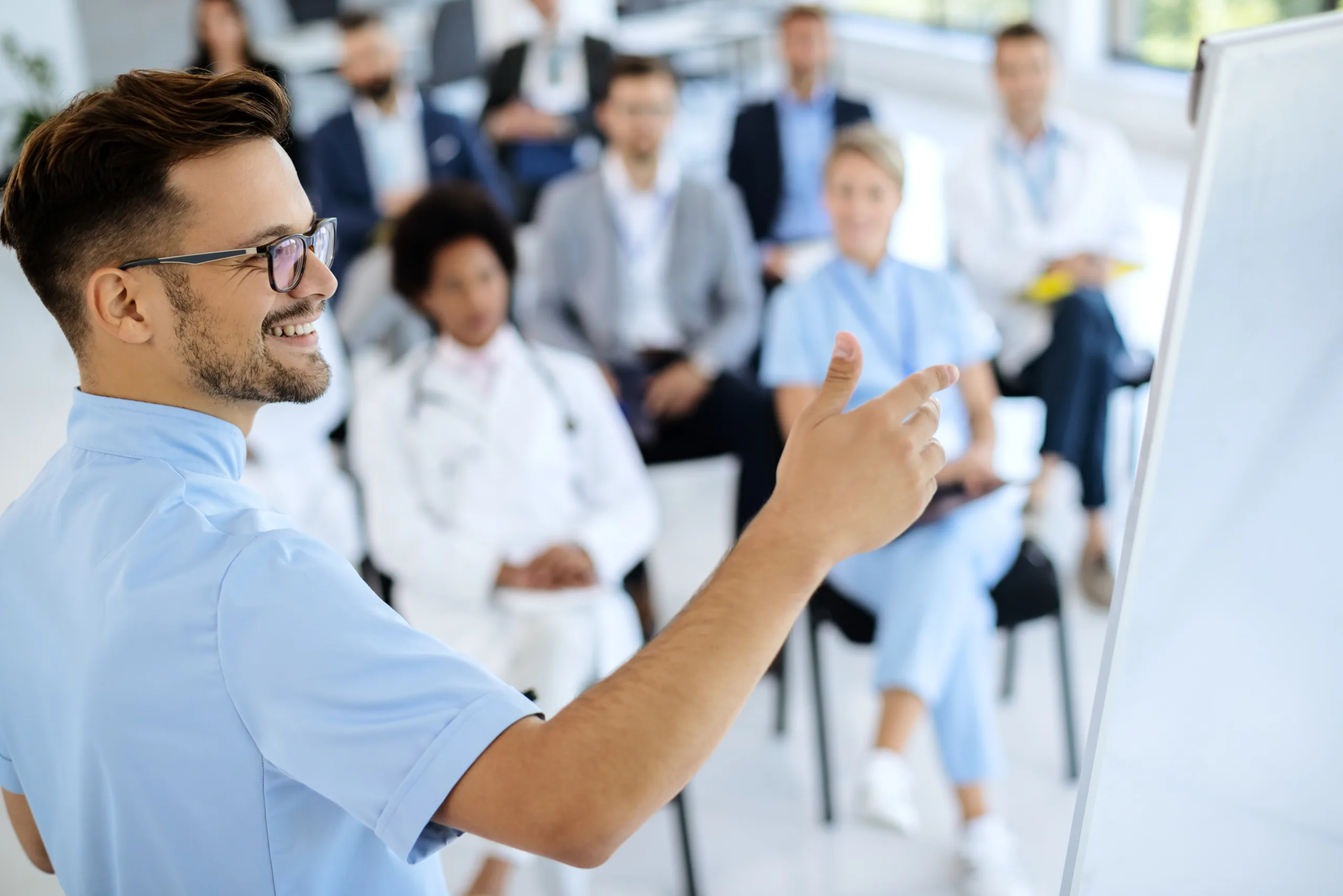 male doctor giving a presentation to group of healthcare workers and business people in board room.