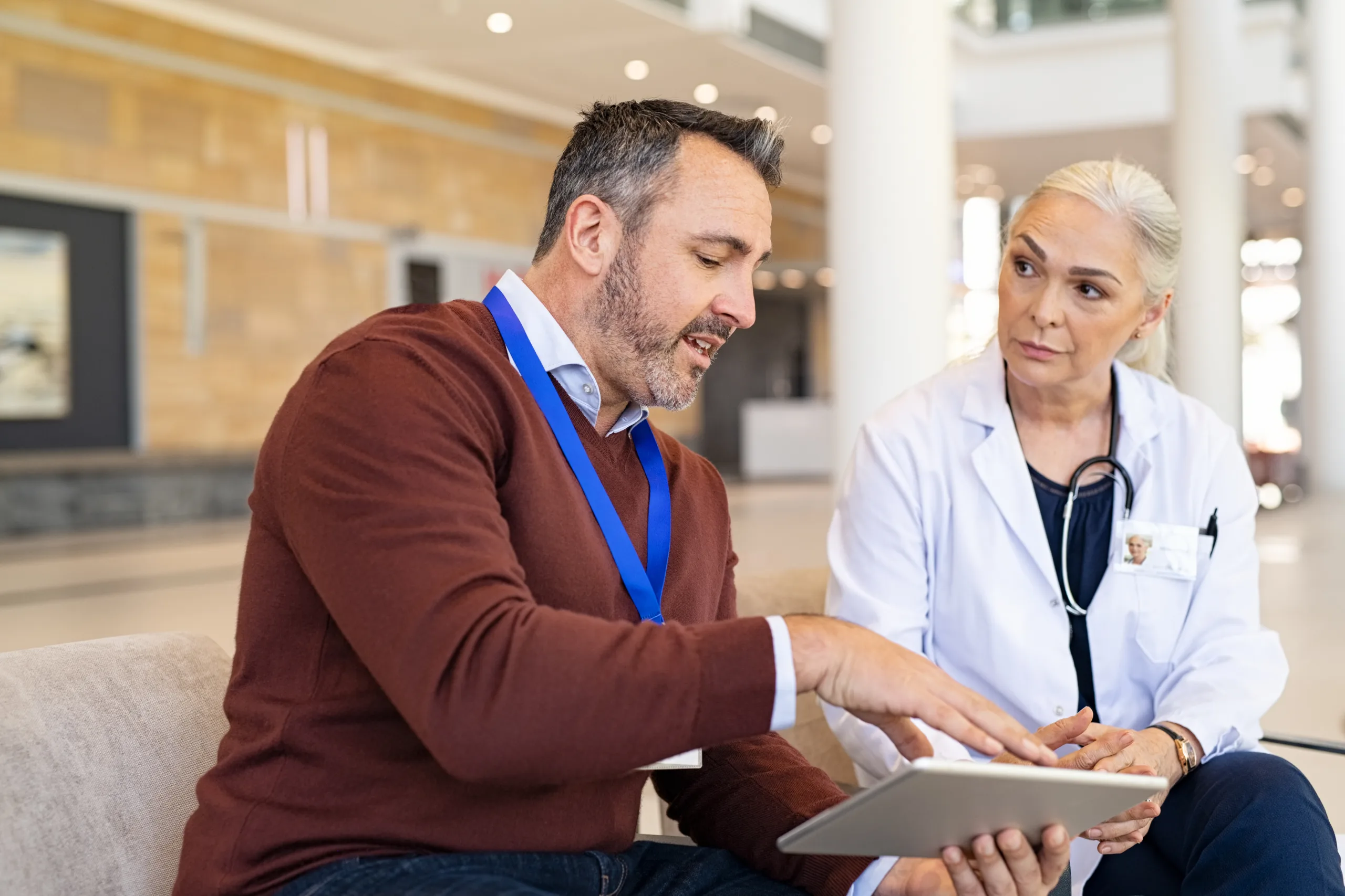 Pharmaceutical sales representative and woman physician having a discussion in hospital hallway.