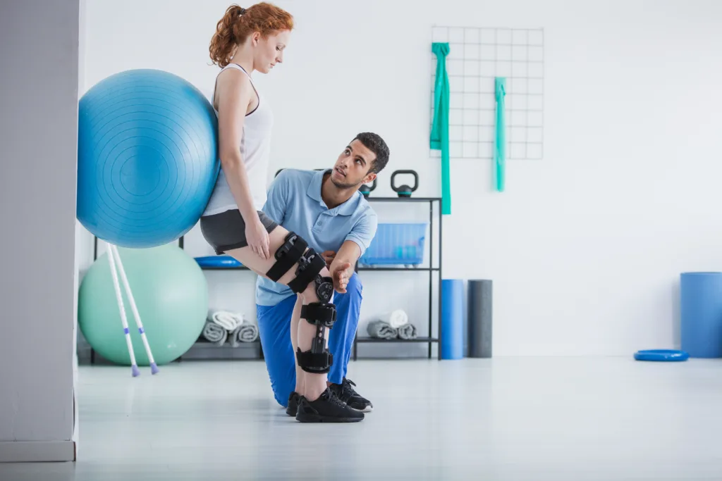 Woman with orthopedic problem exercising with ball while physiotherapist supporting her