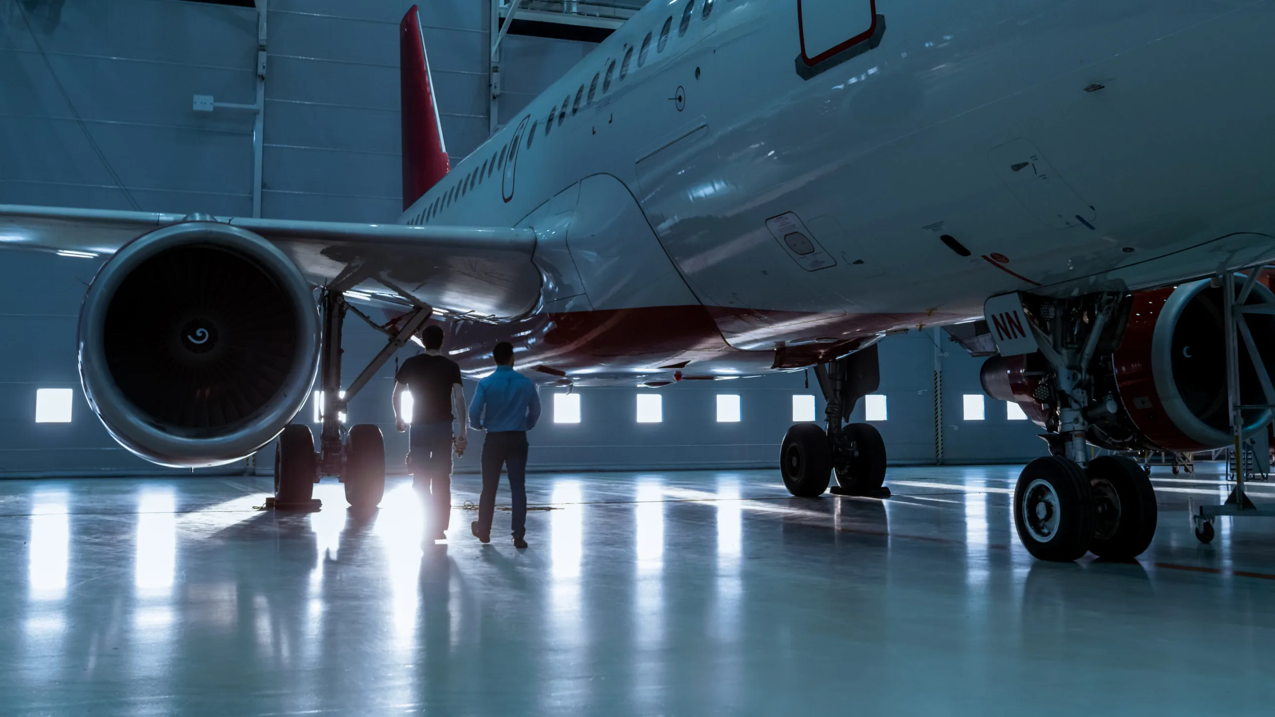 In a Hangar Aircraft Maintenance Engineer Shows Technical Data on Tablet Computer to Airplane Technician