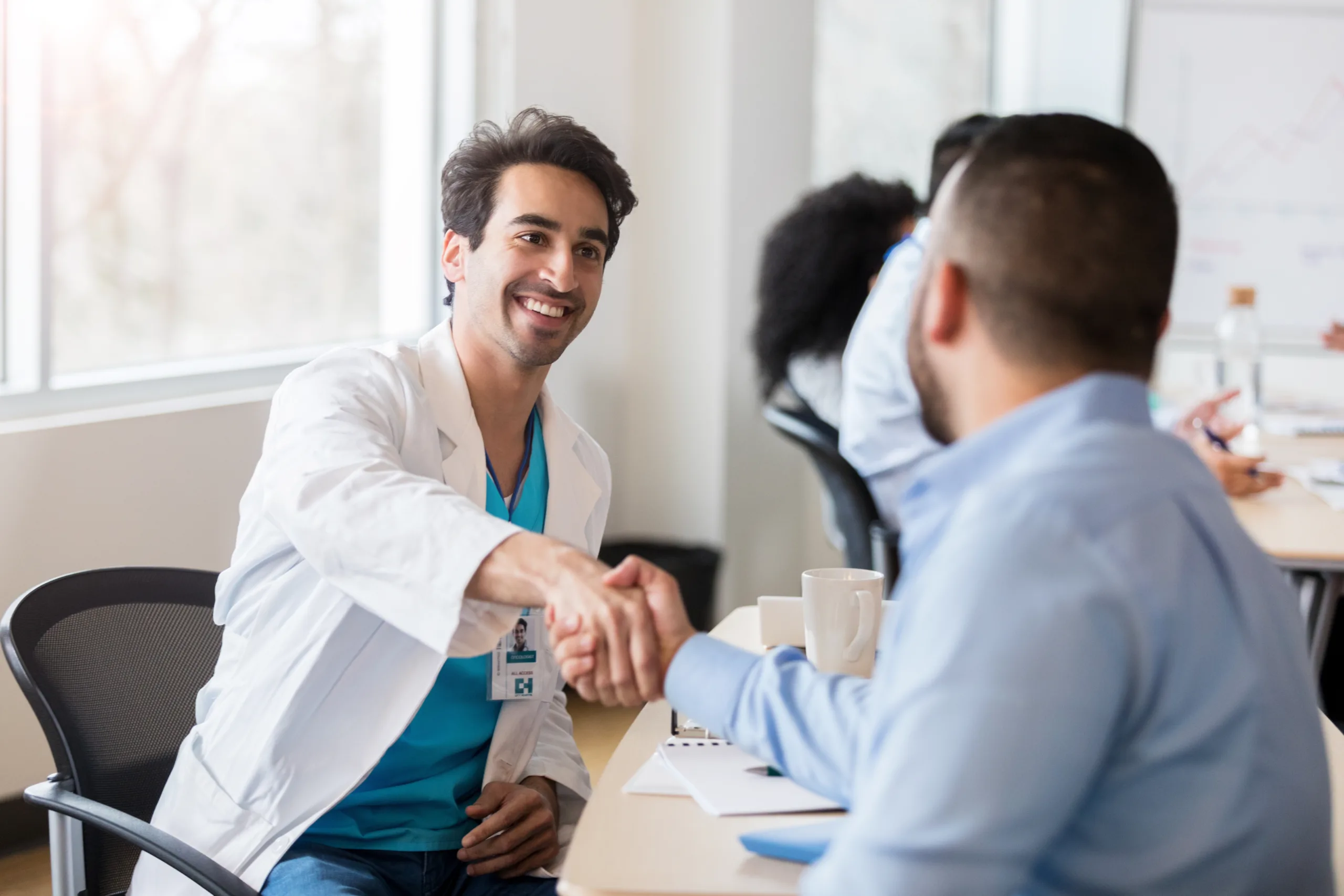 mid adult male doctor shakes hands with a male pharmaceutical sales representative