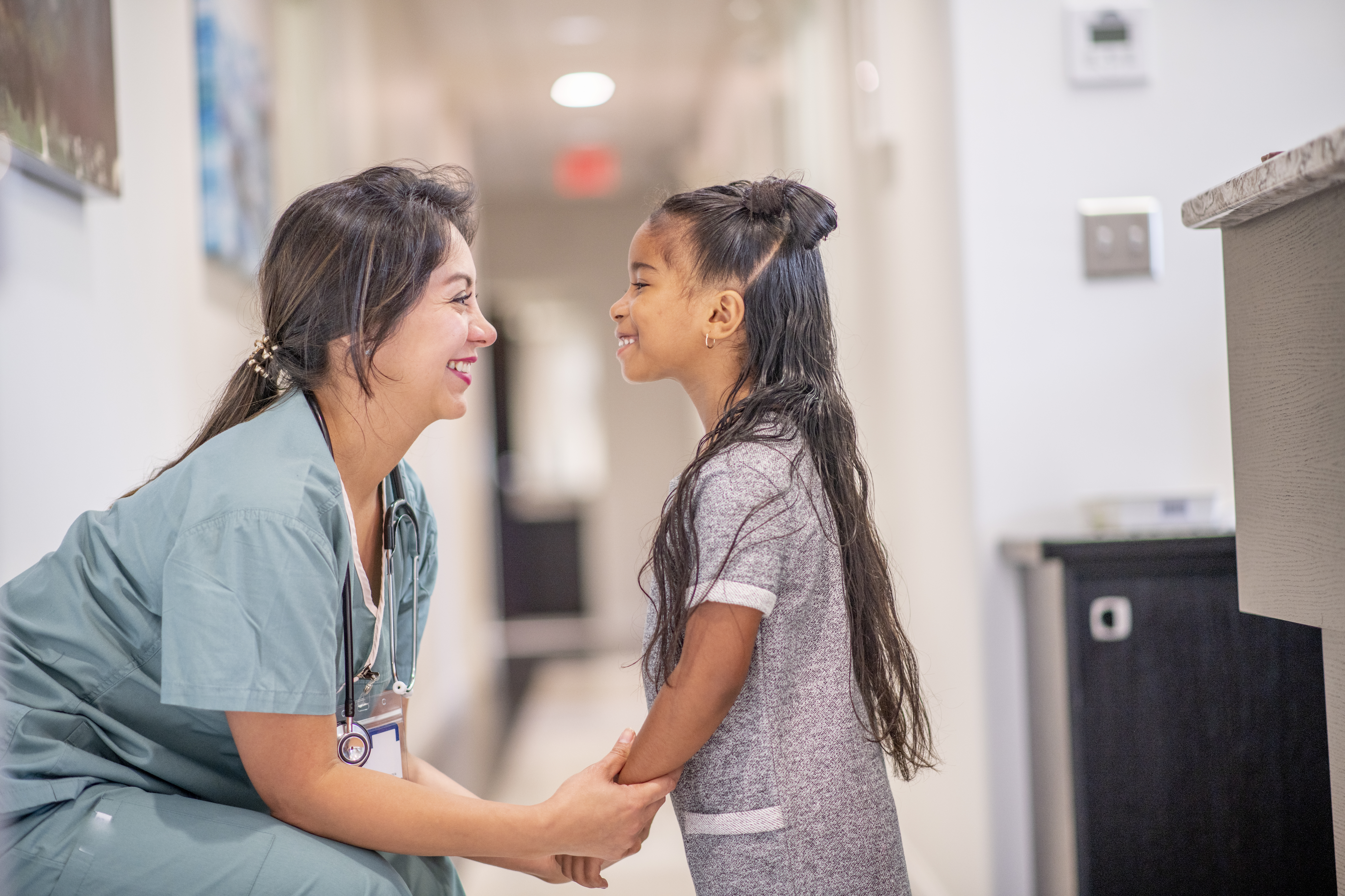Young girl and nurse smiling at each other in hospital