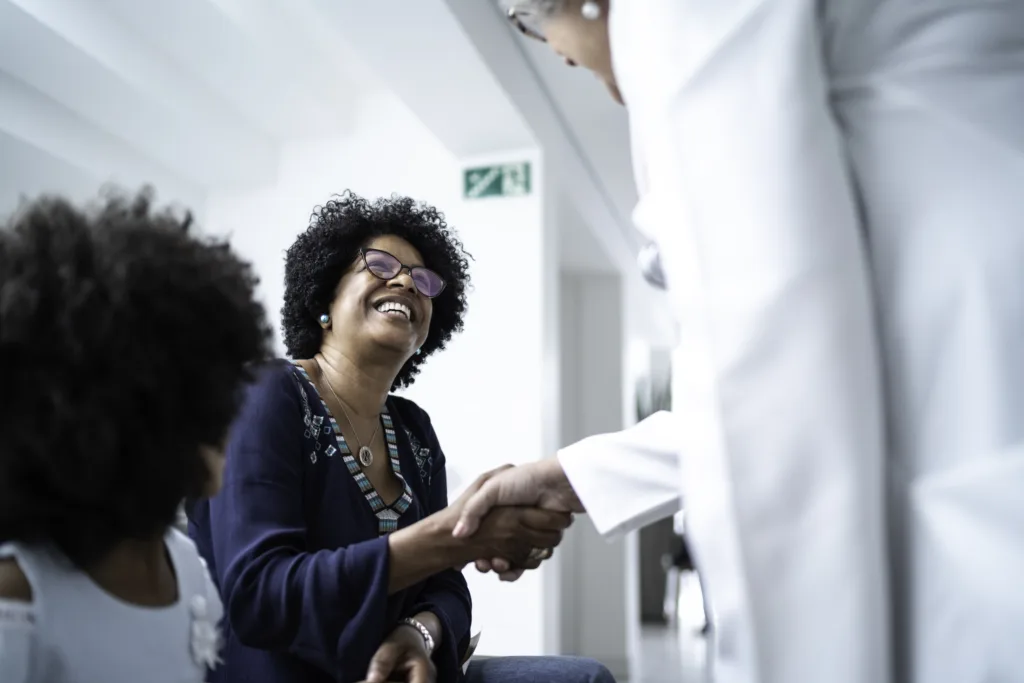 Female senior doctor welcoming / greeting mother and daughter at hospital