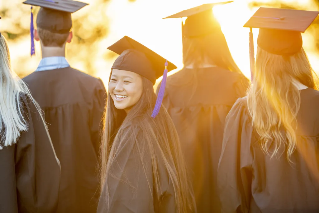 A young female graduate turns around as she poses for a portrait. 