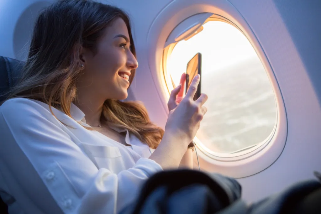 Female traveler taking picture out of airplane window on iPhone