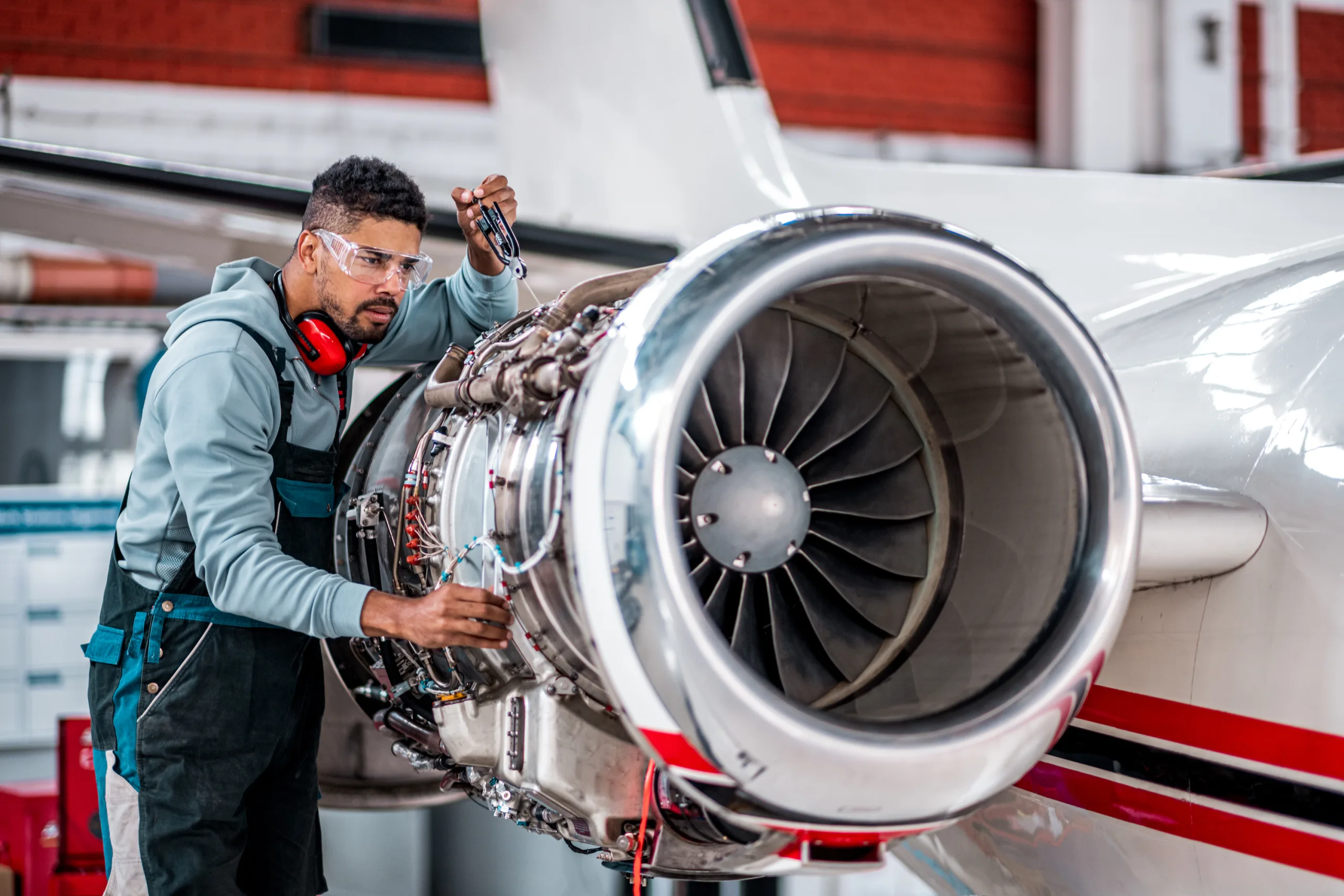 Aircraft mechanic inspecting and checking the technology of a jet engine in the hangar at the airport