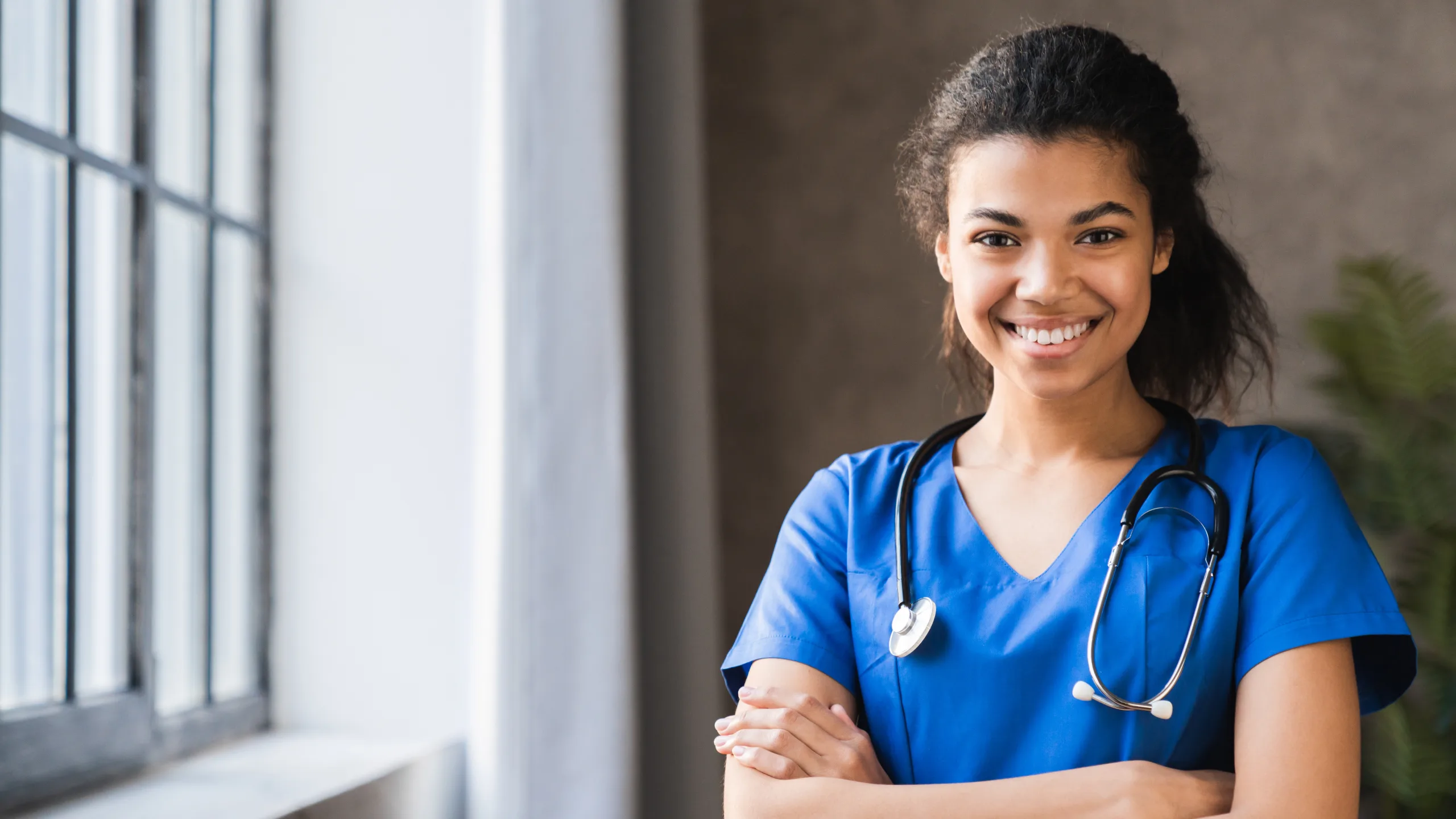 female doctor smiling with stethoscope on and a hospital background